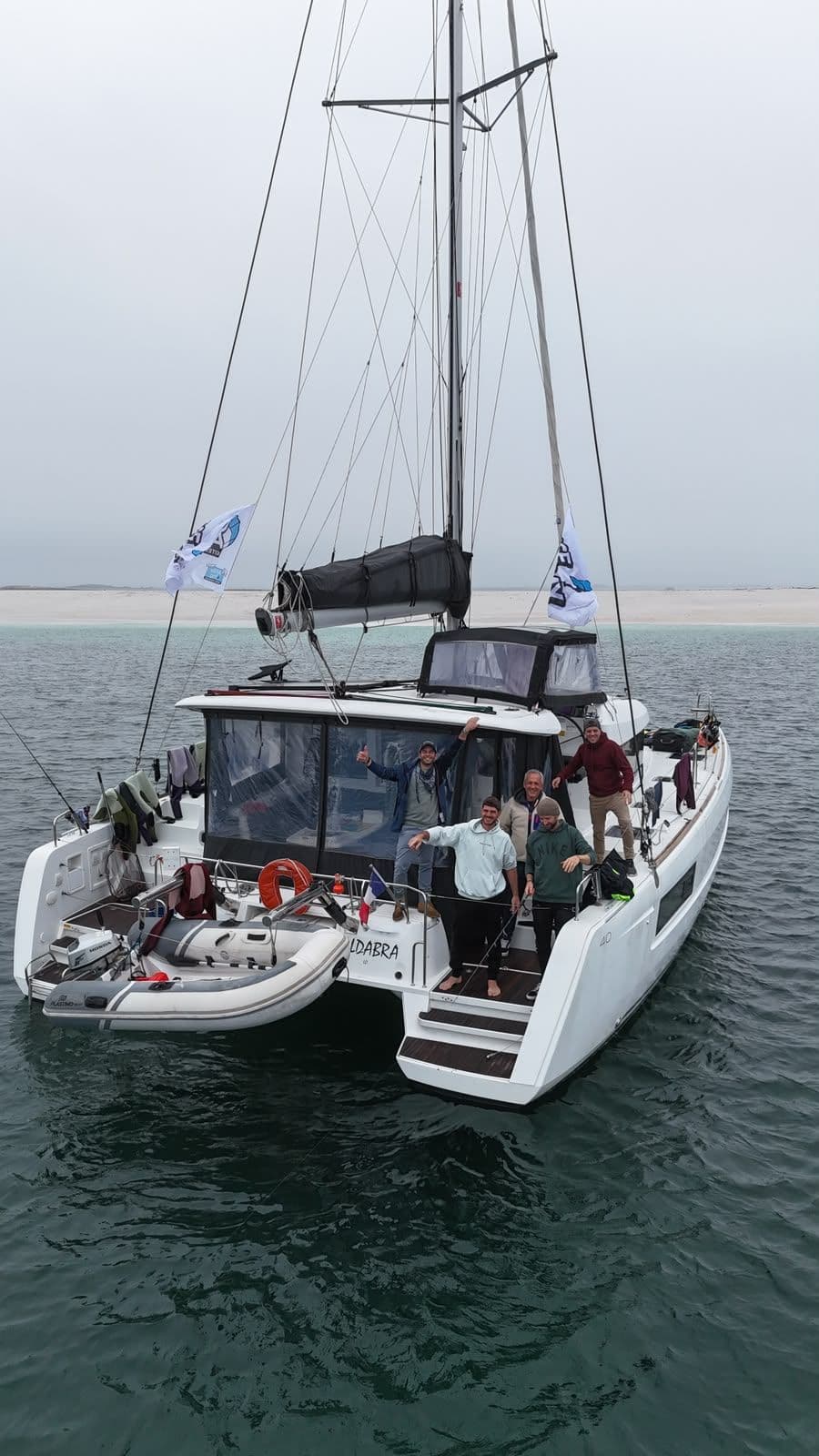 Équipage souriant à l’arrière d’un bateau, vu du ciel